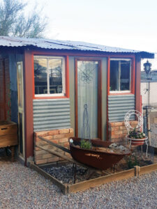 blue shed with brown trim, metal sheeting and brick on front of